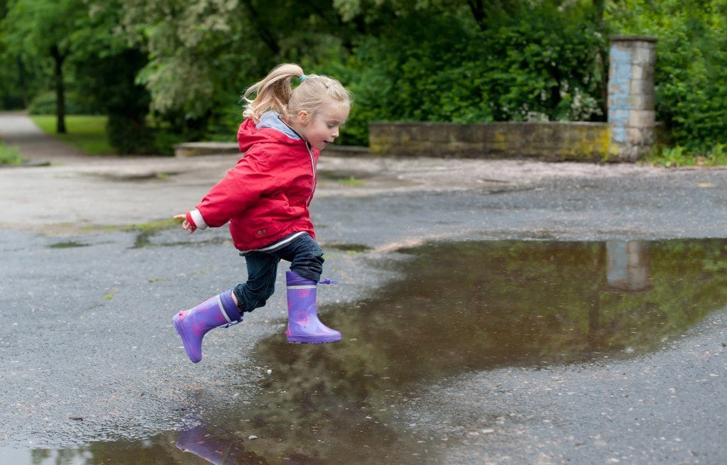 Kid jumping in puddle on a rainy day