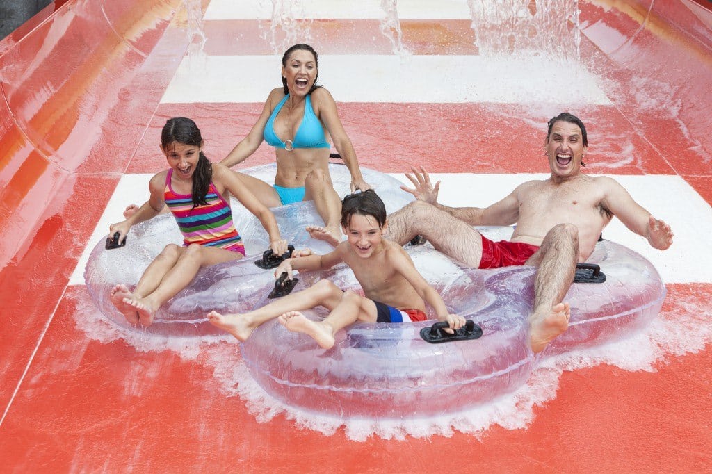Family coming down red slide in water park