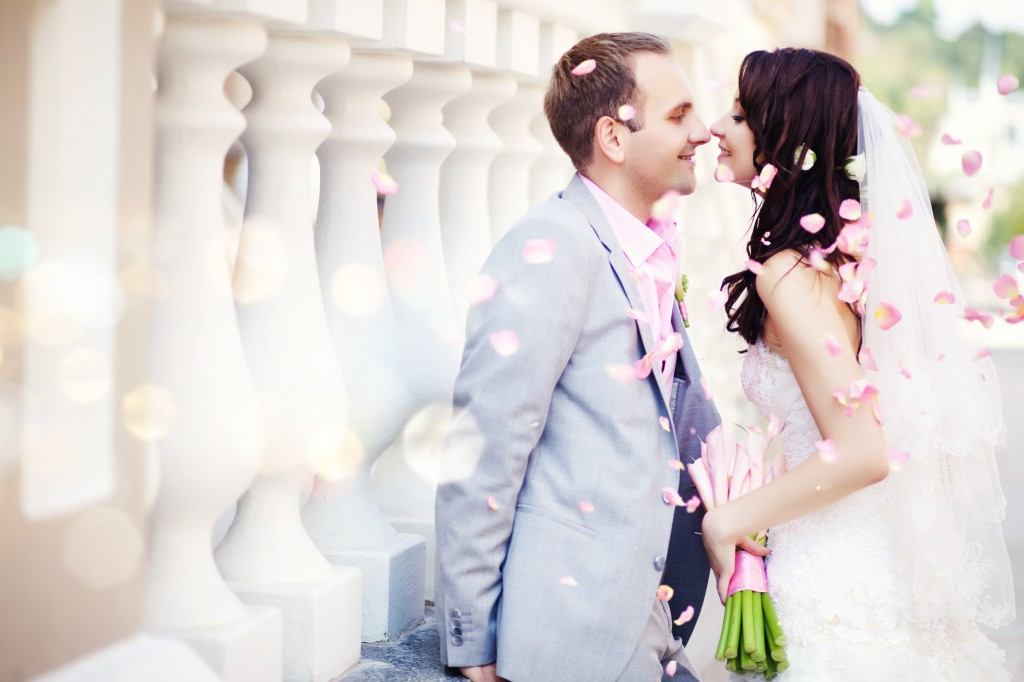 Newly wed couple kissing with pink flower petals