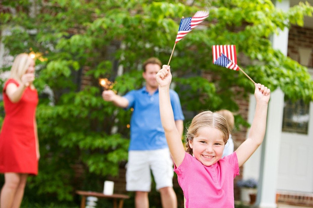 Family holding sparklers and a girl waving two small American flags