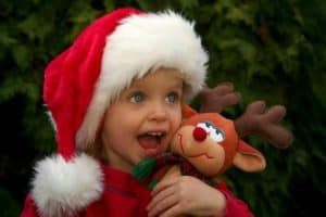 Girl wearing Santa hat and holding reindeer stuffed animal
