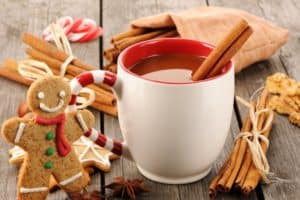 Hot cider with cinnamon sticks and a decorated gingerbread cookie