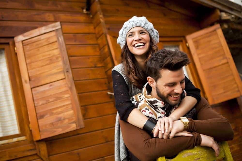 Young happy couple standing outside of a cabin