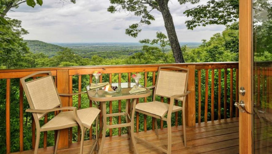 two chairs and a table on the deck of a romantic gatlinburg cabin