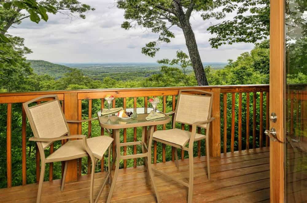 two chairs and a table on the deck of a romantic gatlinburg cabin