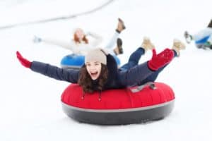 A group of young women snow tubing down a mountain.