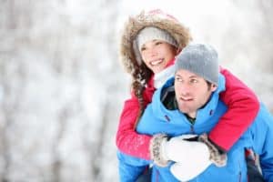 A man giving a woman a piggyback ride during a winter hike.