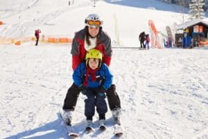 A mother and her young son skiing together.