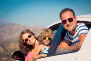 Family wearing sunglasses driving in the mountains.