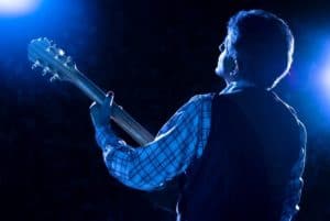 A guitarist on stage under blue lighting.