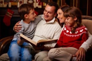 A family reading a Christmas story together on a couch.