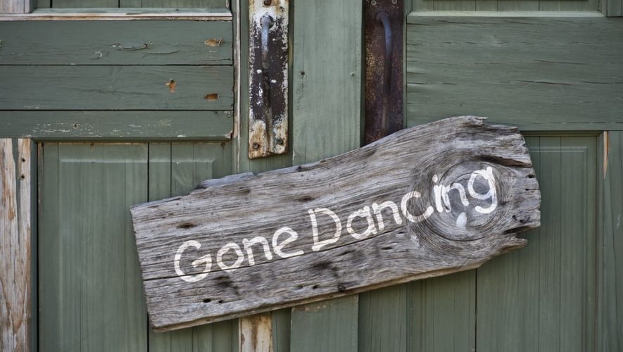 Sign hanging on green door says Gone Dancing